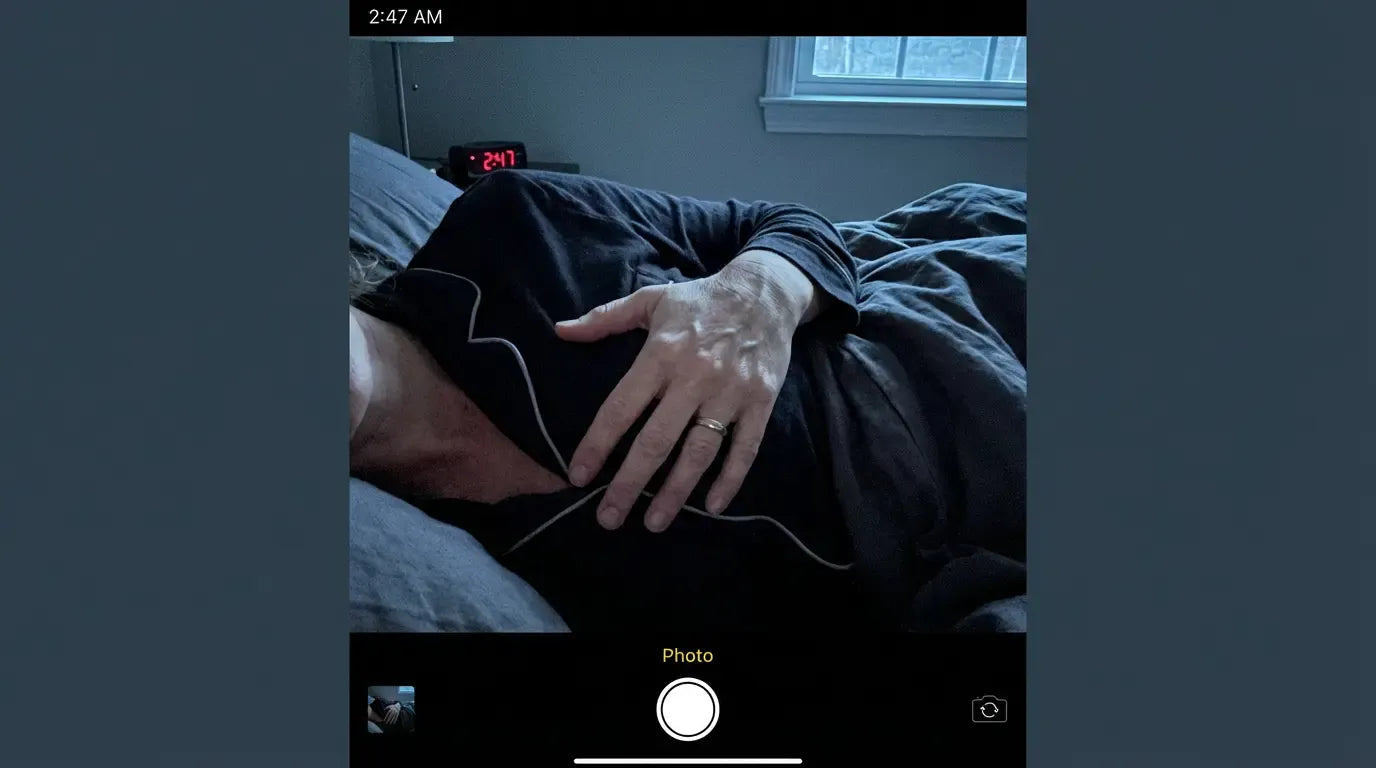A phone showing 2:47am beside a woman lying awake
